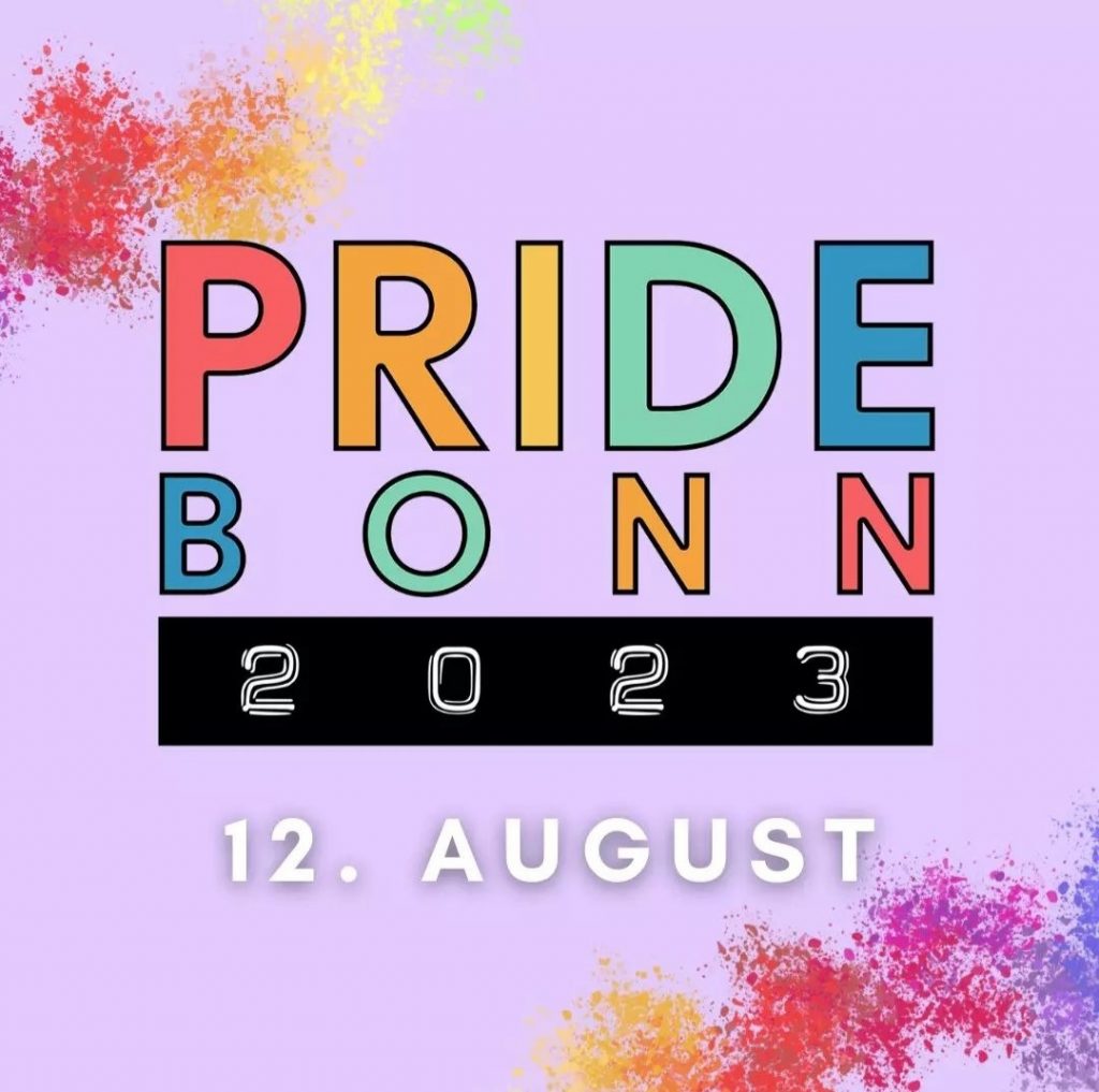 Das Logo der Pride Bonn zeigt den Text "PRIDE BONN" in regenbogenfarbener Schrift. Darunter befindet sich ein schwarzes Rechteck mit "2023" in weiß darauf. Unter dem Block steht ebenfalls in weiß "12. August". Der Hintergrund ist rosa. An der oberen linken Ecke, sowie der unteren rechten befinden sich Farbspritzer in grün, gelb, orange, rot, pink und lila.