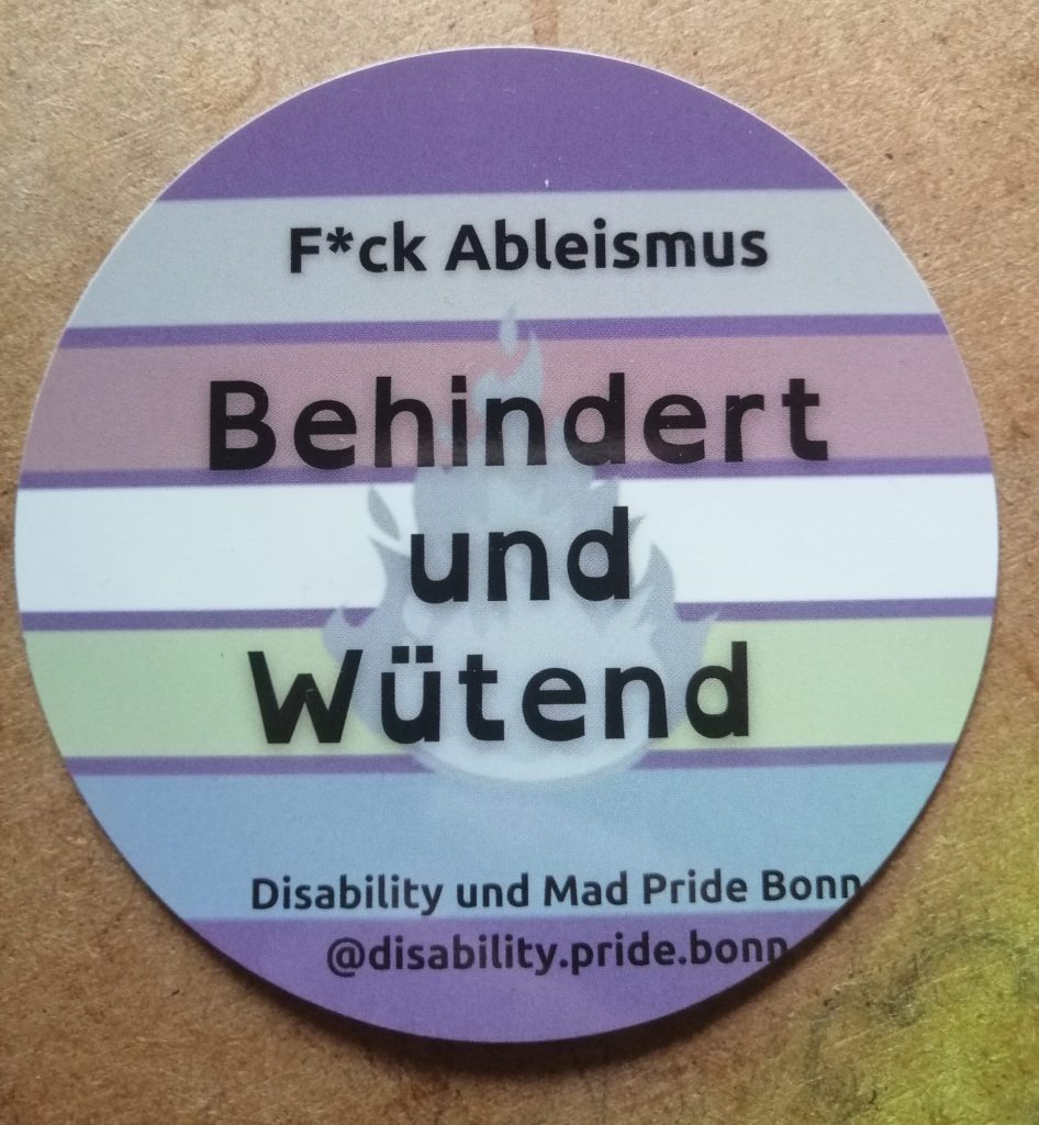 Behindert und Wütend. F*ck Ableismus. Disability und Mad Pride Bonn. Zu sehen ist die Bad Disabled Pride Fahne: lila, grau, braun, weiß, blasses grün, blasses blau und lila (von oben nach unten gestreift).