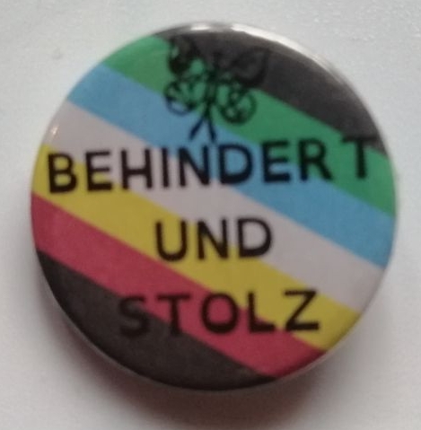 Behindert und Stolz mit einer Behinderten Pride Fahne und einem CIMND* Schmetterling.