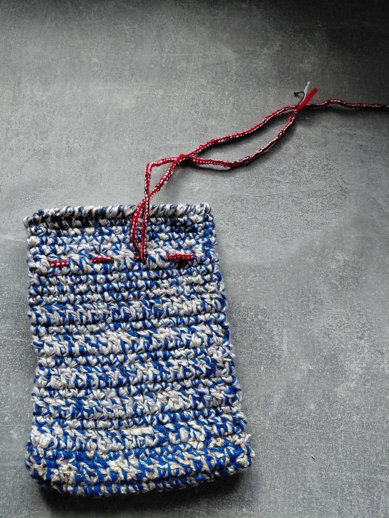 Ein blau-weißes selbst gehäkelte Säckchen.